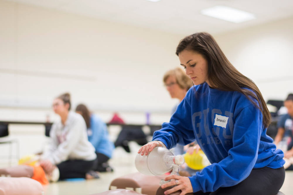 Students practice with airway devices on medical manikins in a classroom
